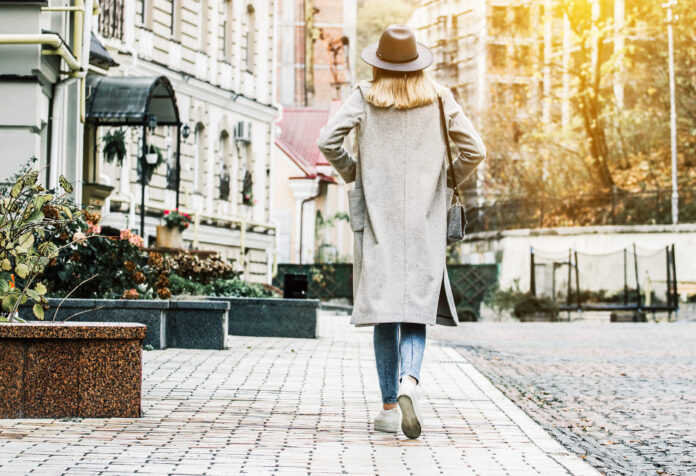 Back View Of Stylish Young Woman In Coat And Hat Keeping Hands I