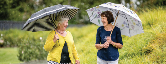 two women walking with umbrellas through Vines at Bethlehem grounds