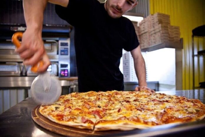 man cutting a pizza